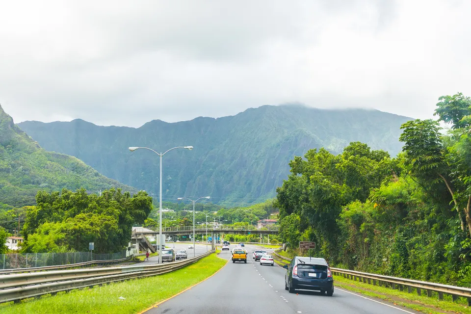 Traffic on Hawaii highway with green mountains in background
